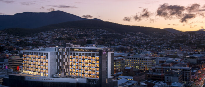 Arial shot of the Crowne Plaza Hobart. A sprawling city with mountains on the horizon