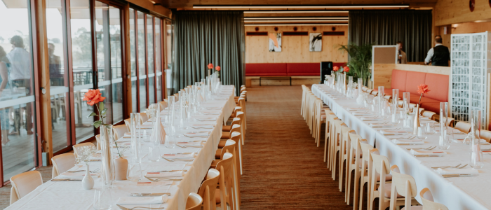 Long dining tables set for an event in a bright function space at Iron Creek Bay Estate