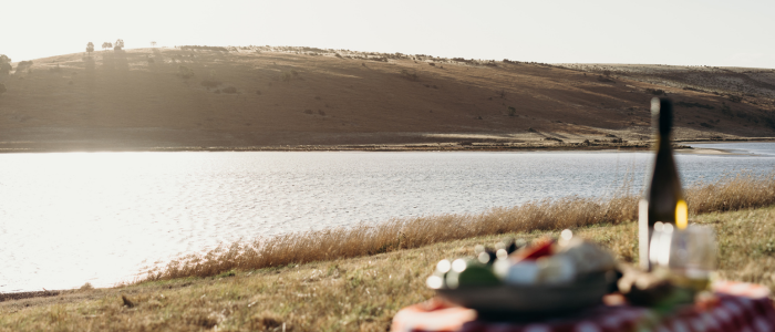 Picnic setup by the water at Iron Creek Bay Estate with hills in the background
