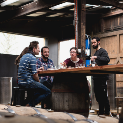 A group of guests take part in a guided cider tasting around a timber table inside Willie Smith’s rustic Apple Shed
