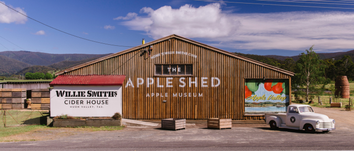 Exterior of Willie Smith’s Apple Shed and Cider House in the Huon Valley, with a vintage truck and mountains behind it.